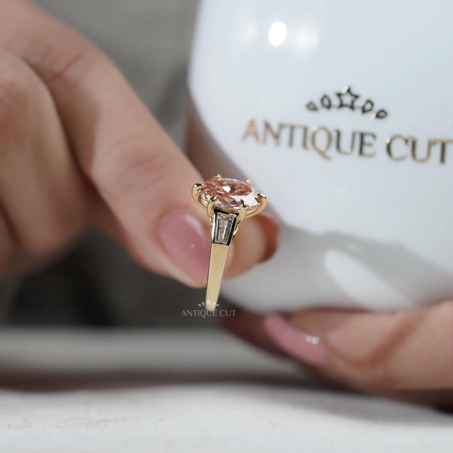 Close-up of a hand wearing a rose gold ring with a pink gemstone.
