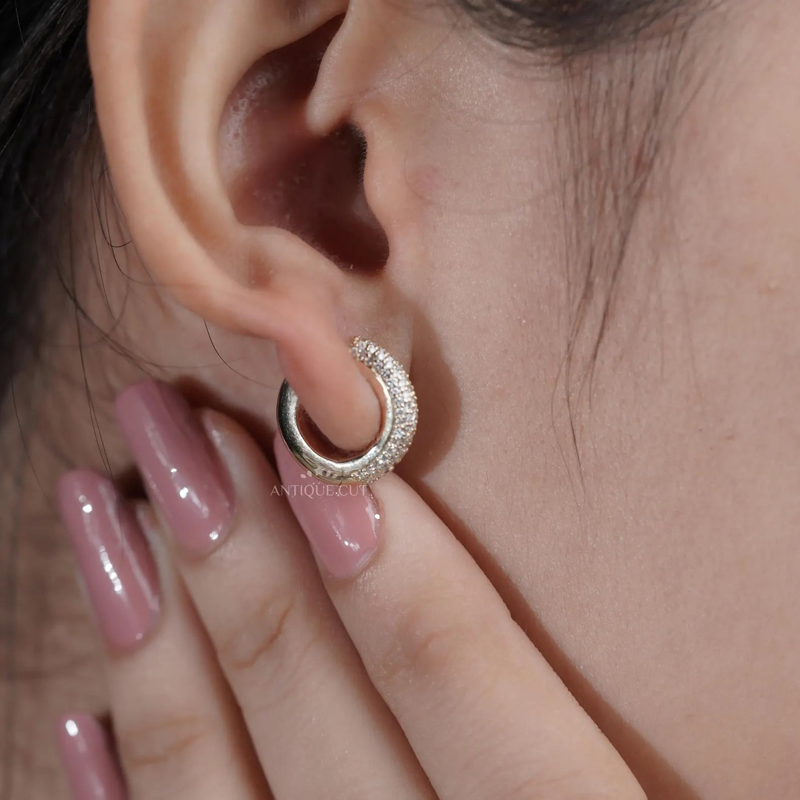 Close-up of a person wearing a gold hoop earring
