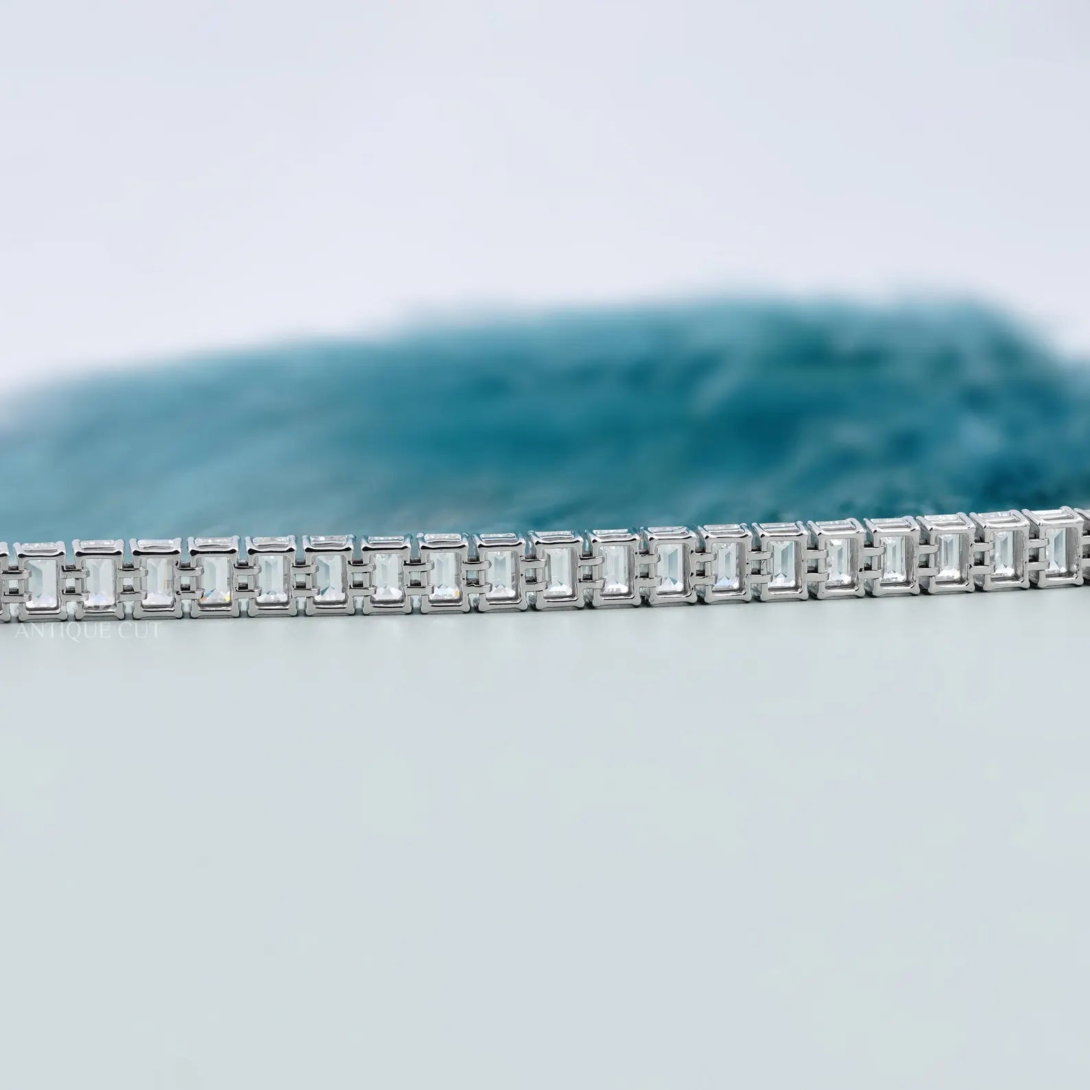 Silver bracelet with square-cut stones on a light gray background