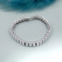 Silver bracelet with square-cut stones on a light gray background