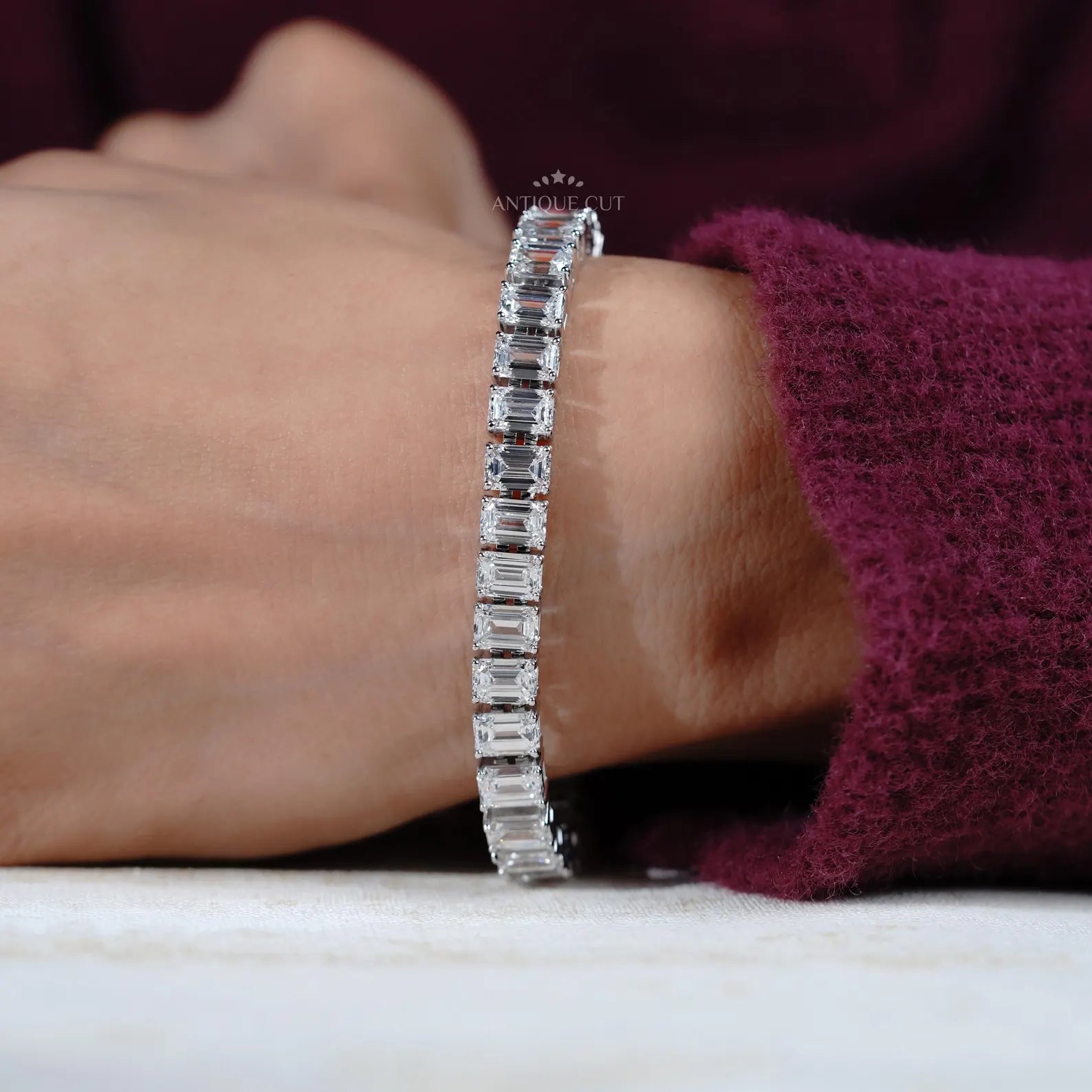 Diamond bracelet with emerald-cut diamonds on a gradient blue and gray background