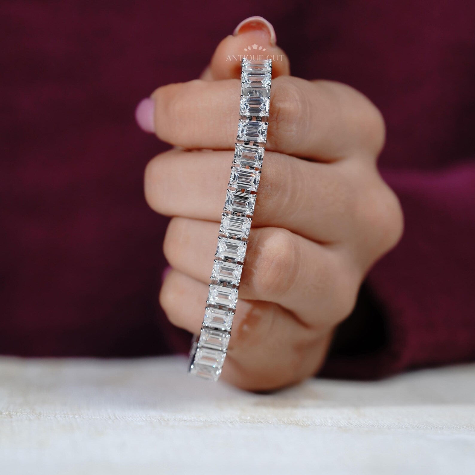 Diamond bracelet with emerald-cut diamonds on a gradient blue and gray background