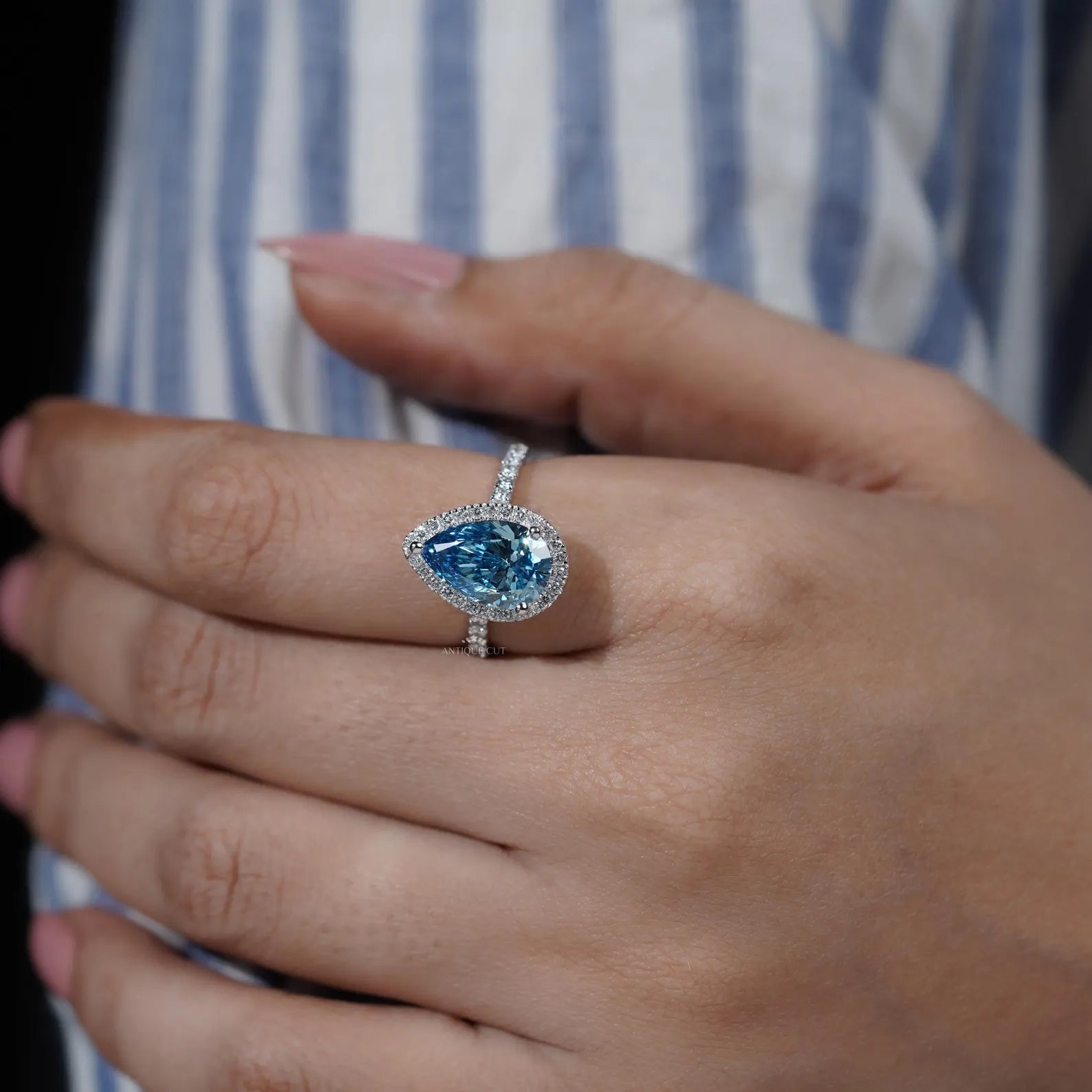Blue diamond halo ring with three round prong setting