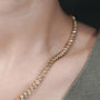 A gold necklace with diamonds on a person's neck