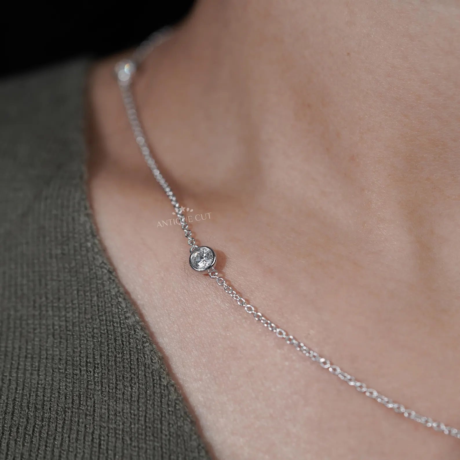 Silver necklace with small diamonds on a person wearing a green top
