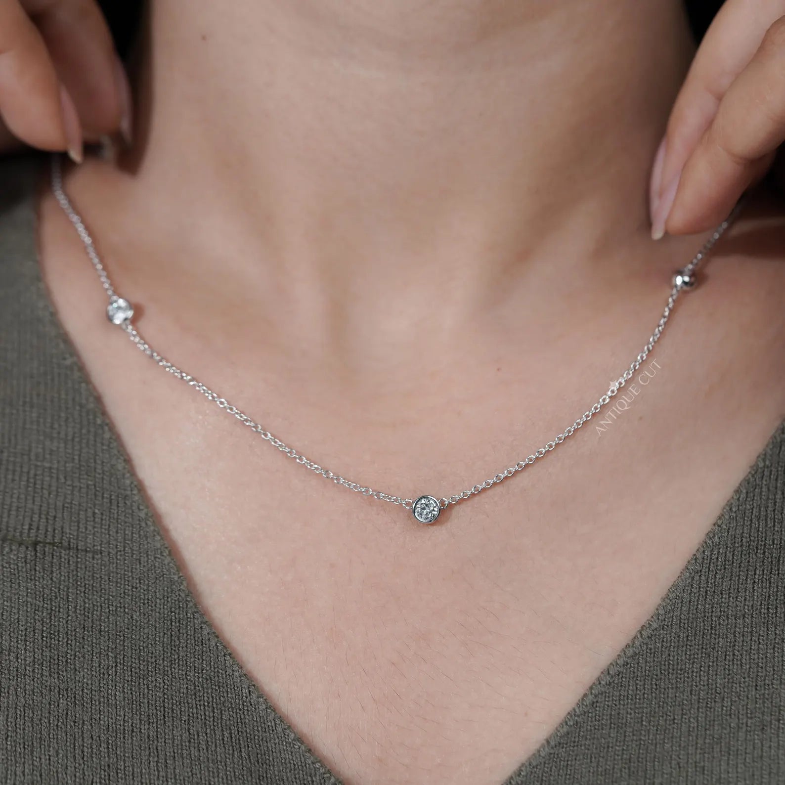 Silver necklace with small diamonds on a person wearing a green top