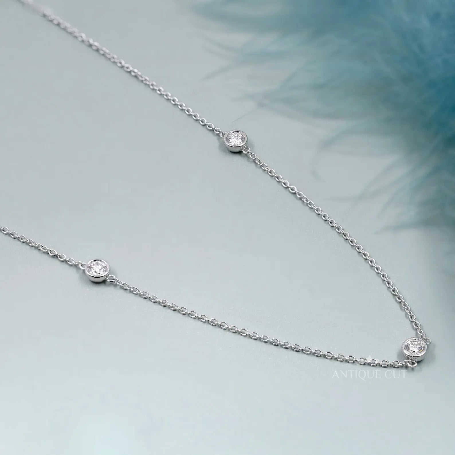 Silver necklace with small diamonds on a person wearing a green top