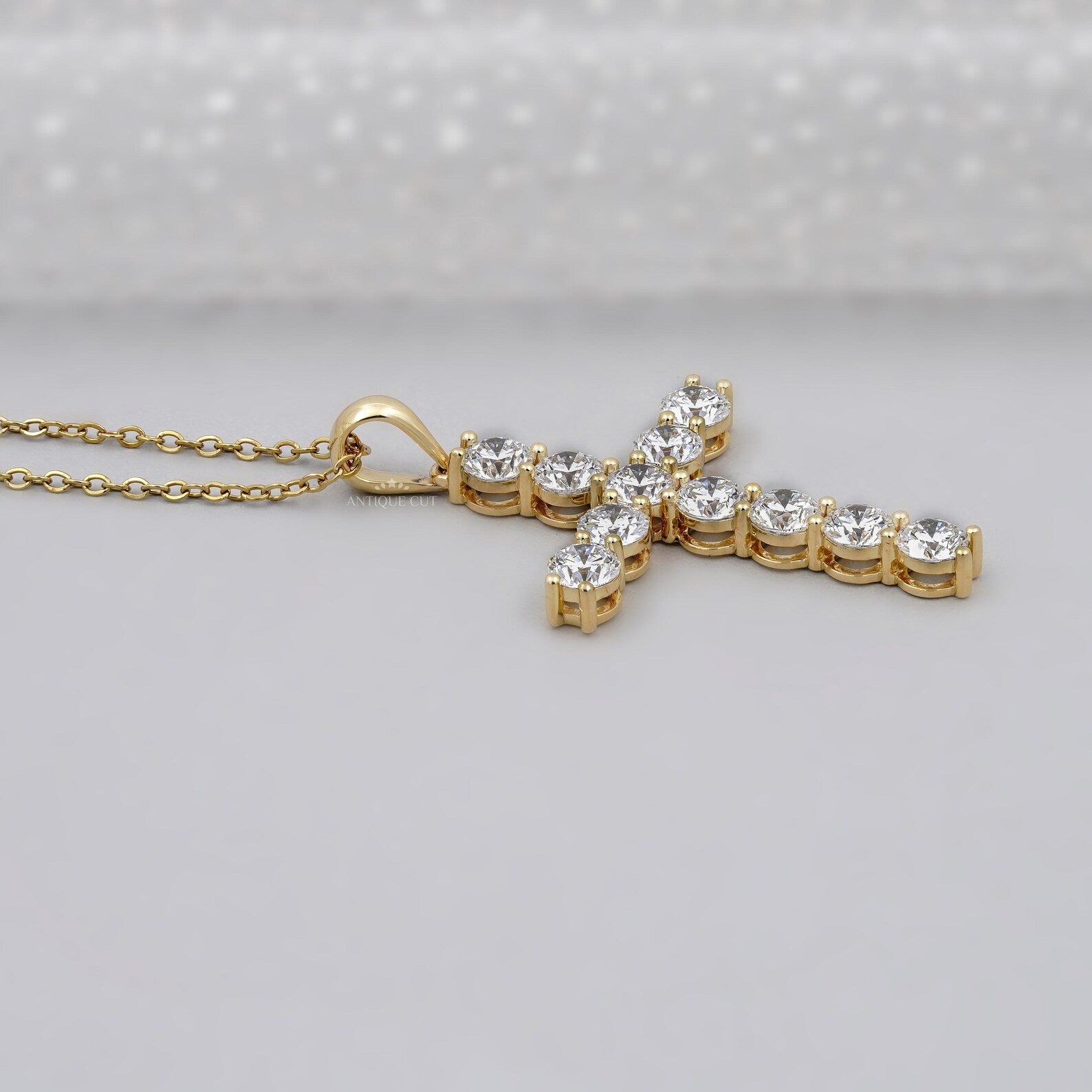 Gold cross necklace with clear stones on a gray background