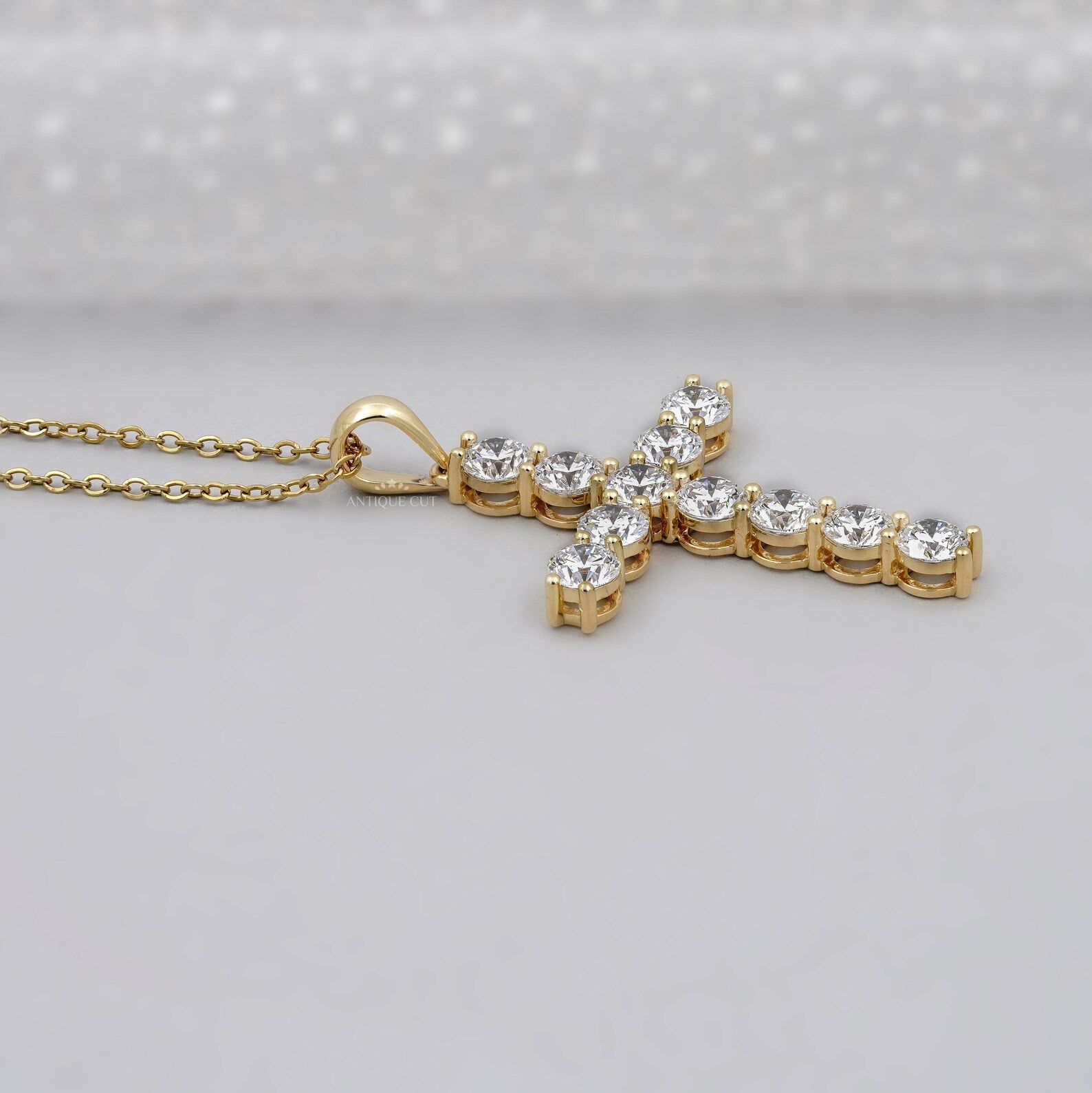 Gold cross necklace with clear stones on a gray background