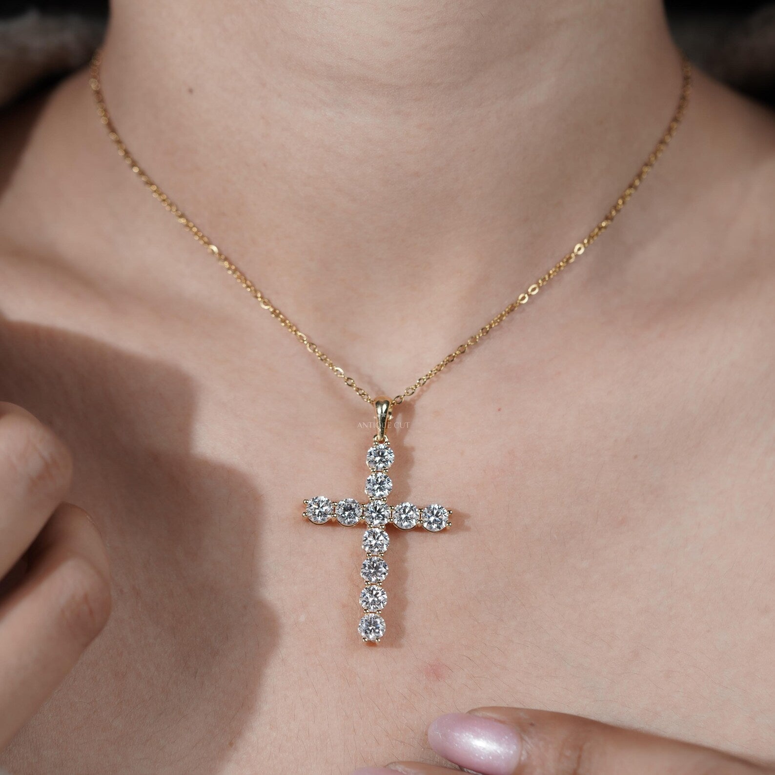 Gold cross necklace with diamonds on a person's neck

