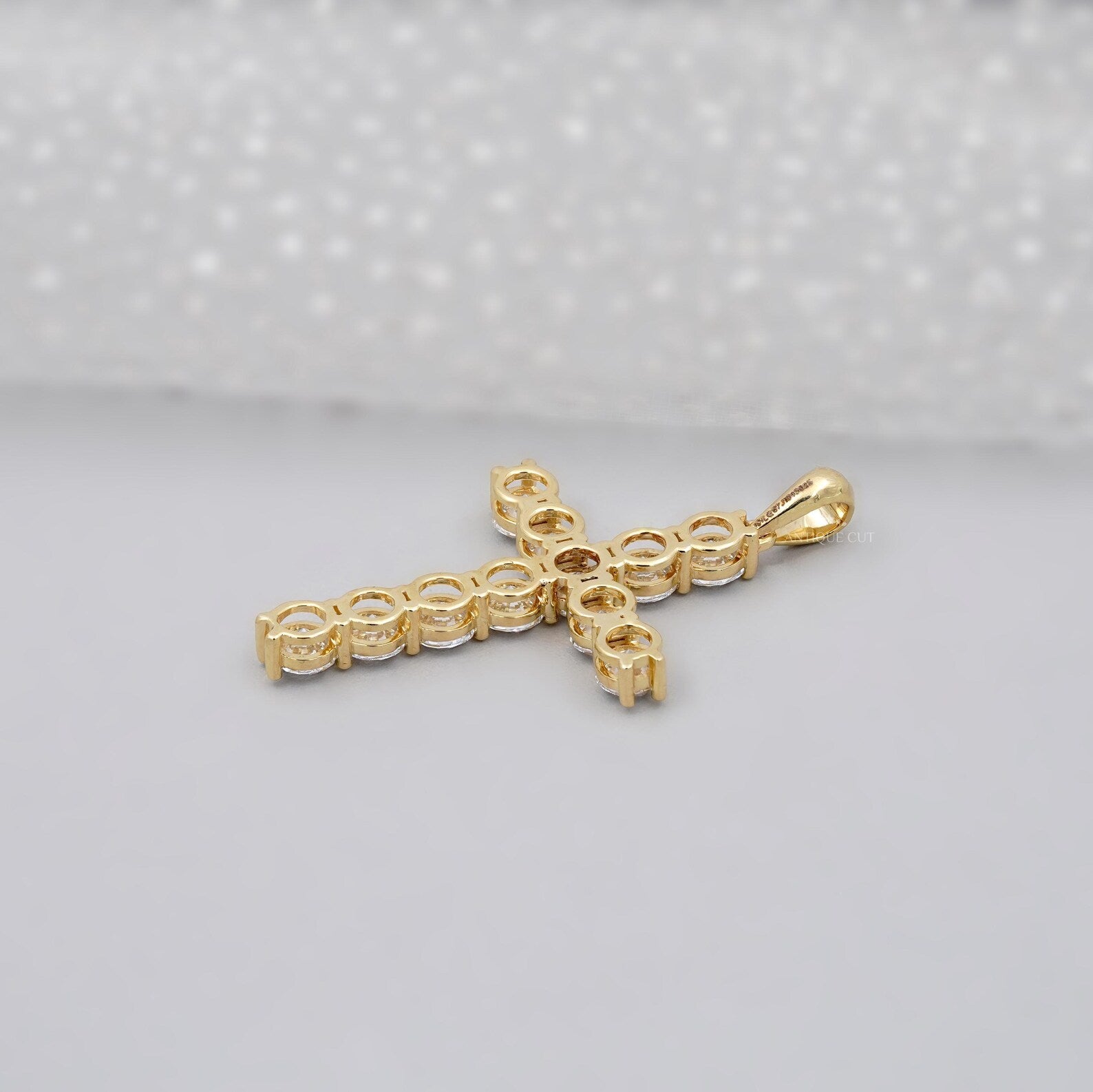 Gold cross necklace with clear stones on a gray background