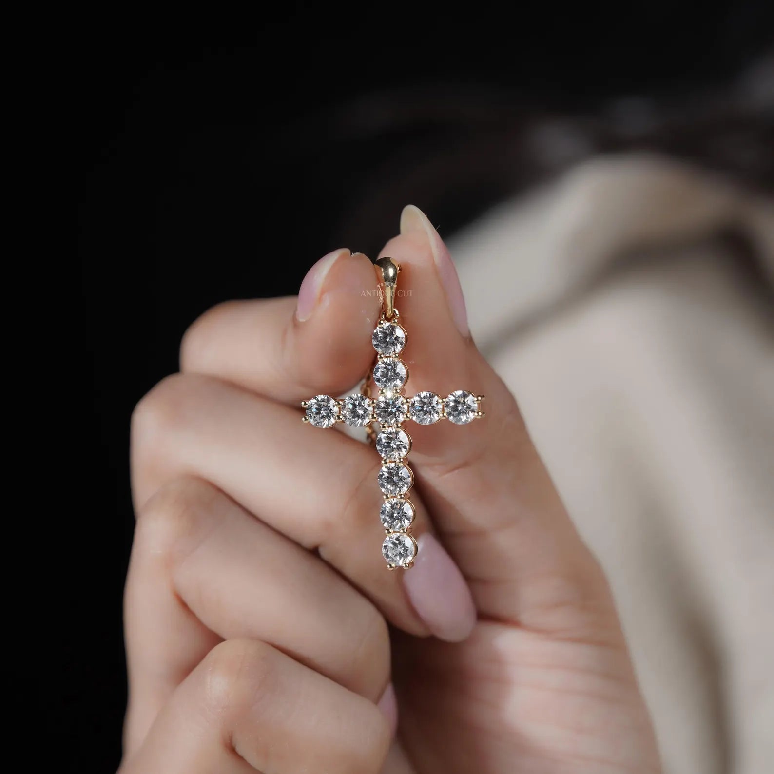 Gold cross necklace with clear stones on a gray background