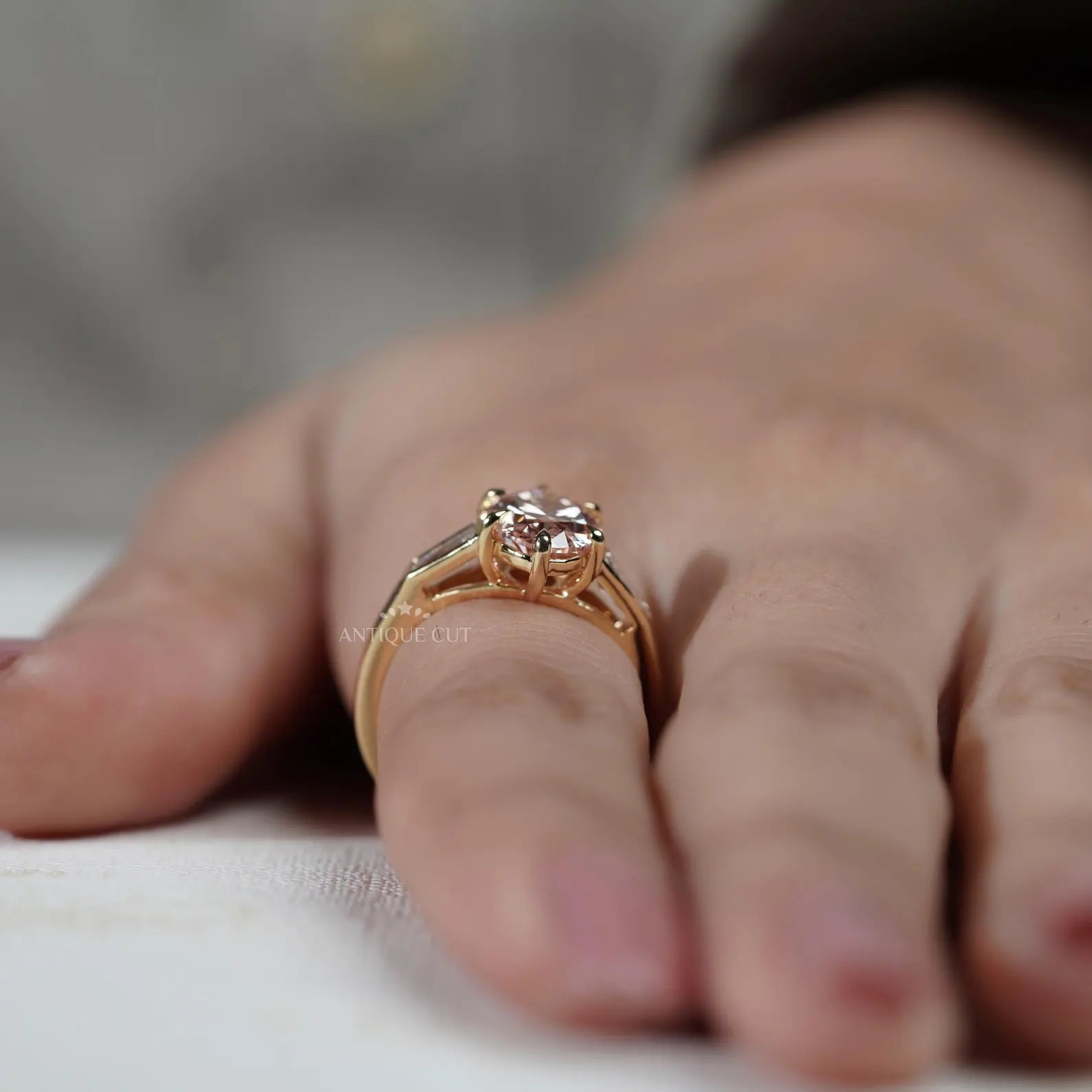 Close-up of a hand wearing a rose gold ring with a pink gemstone.
