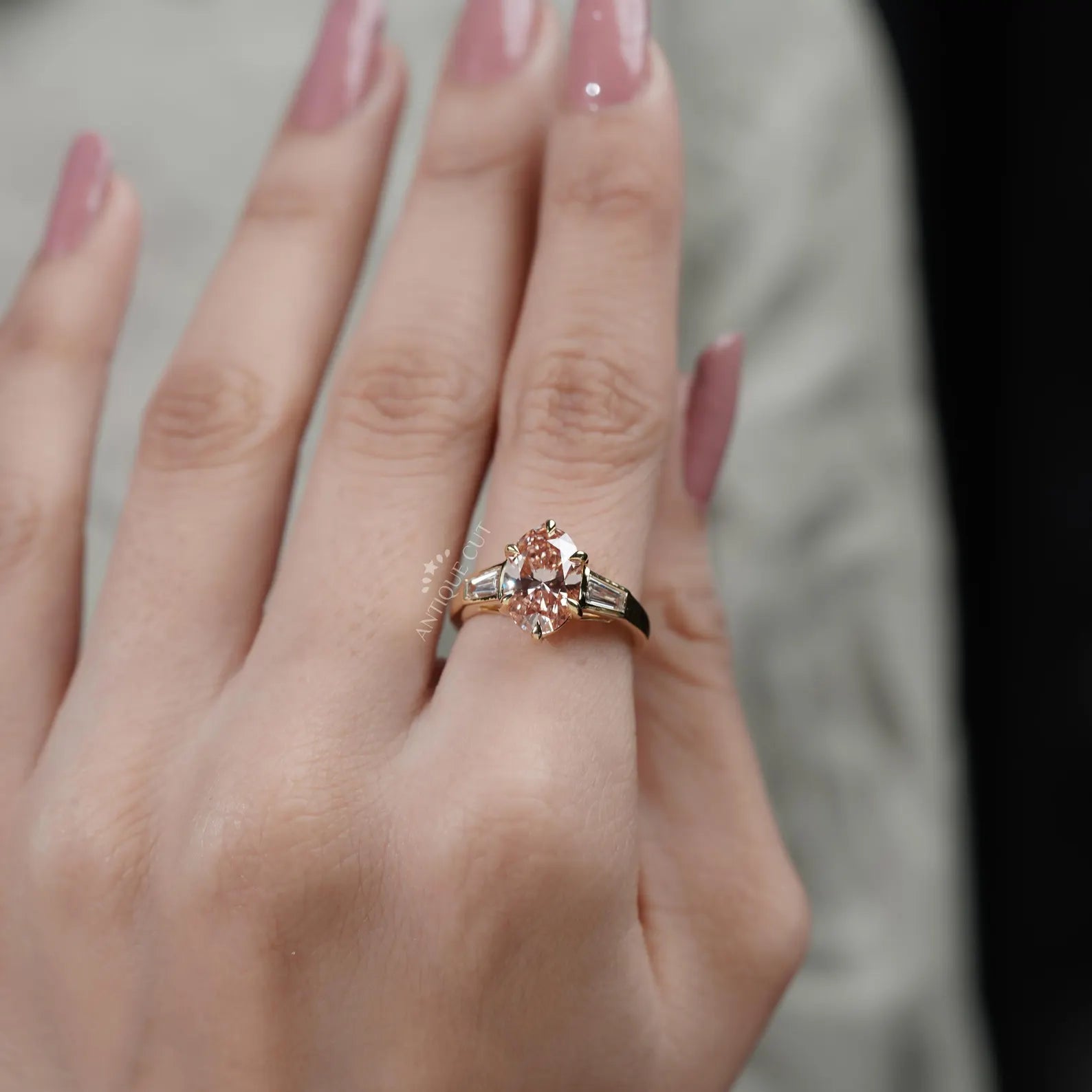 Close-up of a hand wearing a rose gold ring with a pink gemstone.
