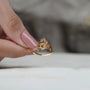 Close-up of a hand wearing a rose gold ring with a pink gemstone.
