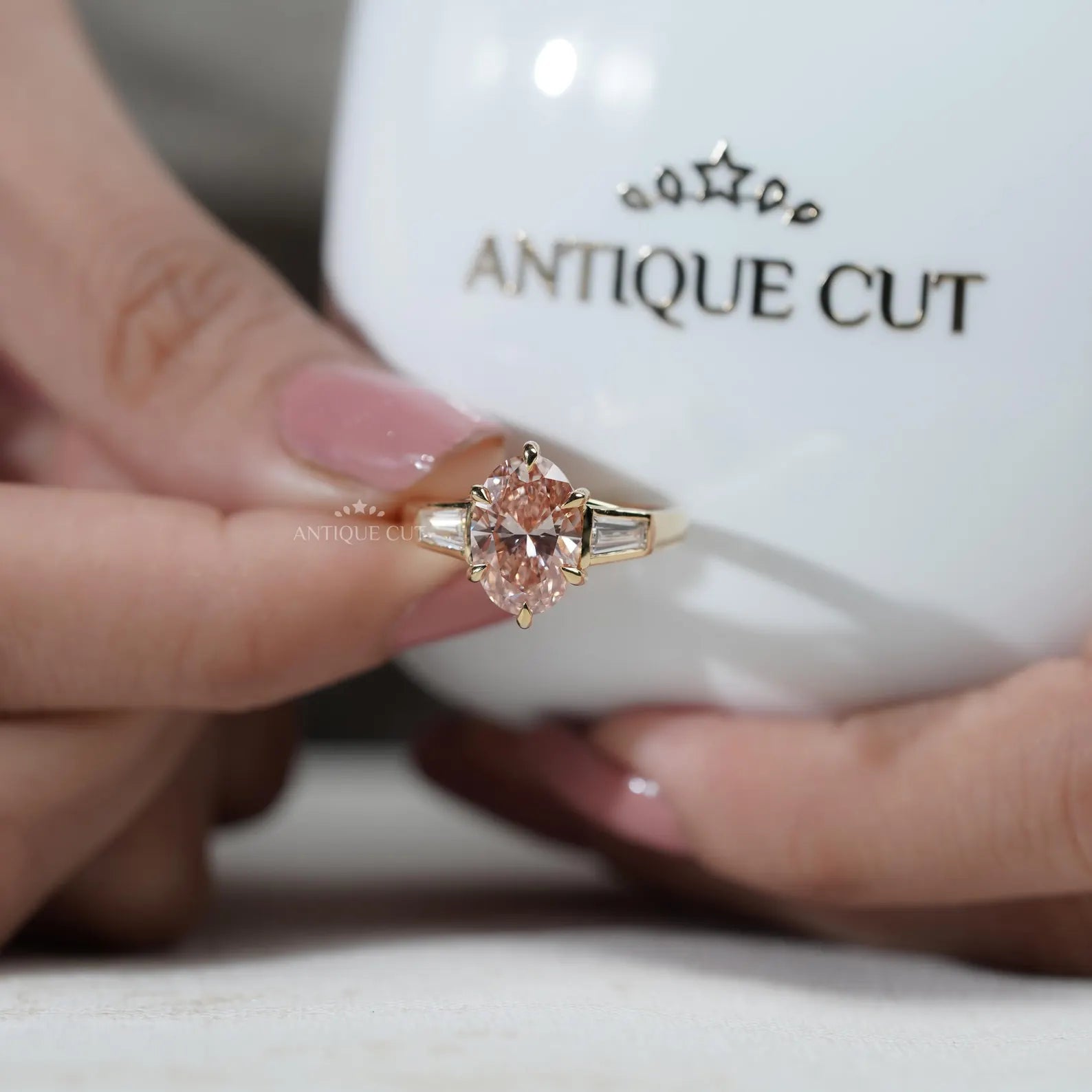 Close-up of a hand wearing a rose gold ring with a pink gemstone.
