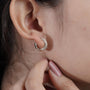 Close-up of a person wearing a gold hoop earring