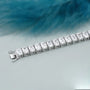 Diamond bracelet with emerald-cut diamonds on a gradient blue and gray background
