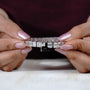 Diamond bracelet held between two hands with a blurred background

