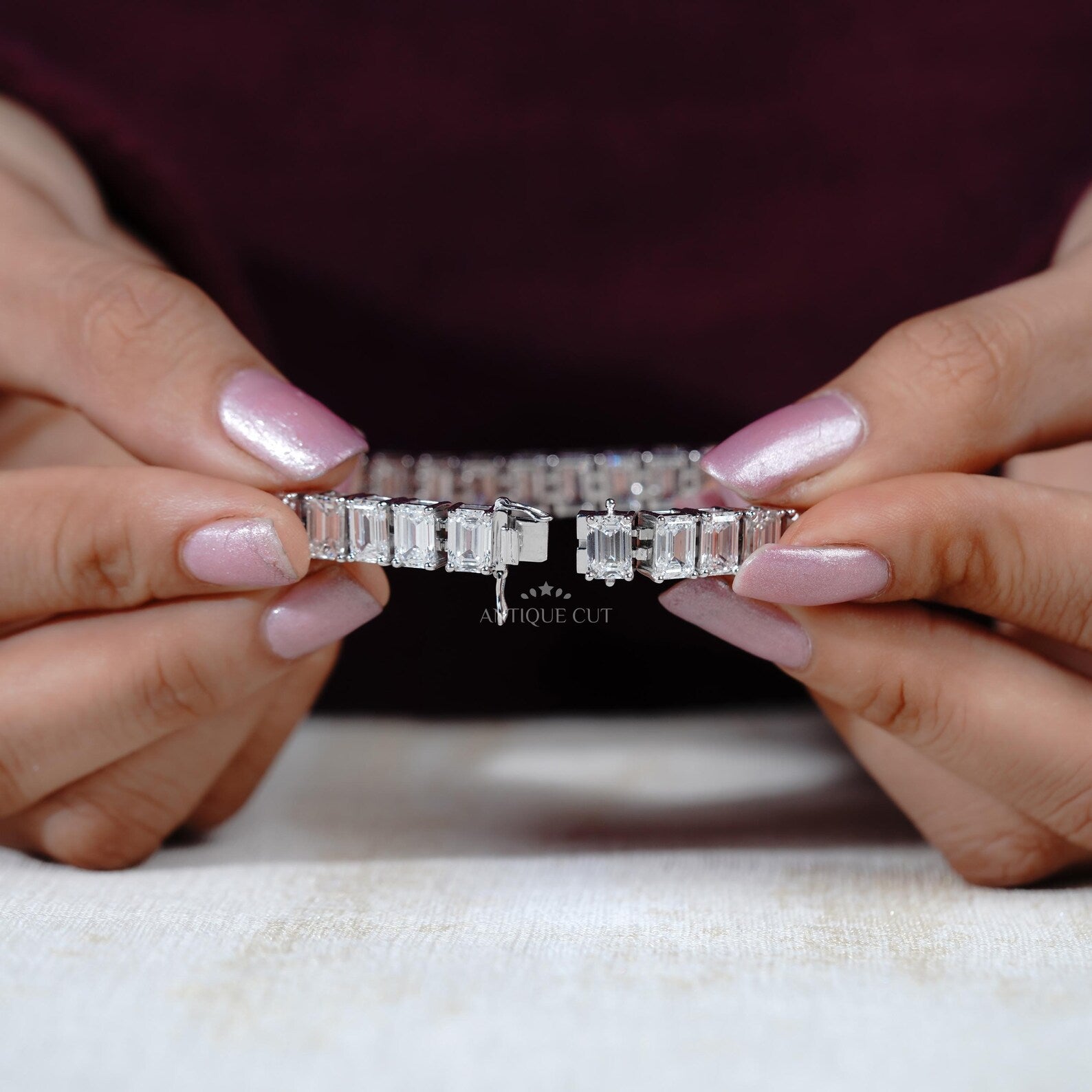 Diamond bracelet held between two hands with a blurred background

