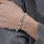 Silver bracelet with clear stones on a wrist against a gray background