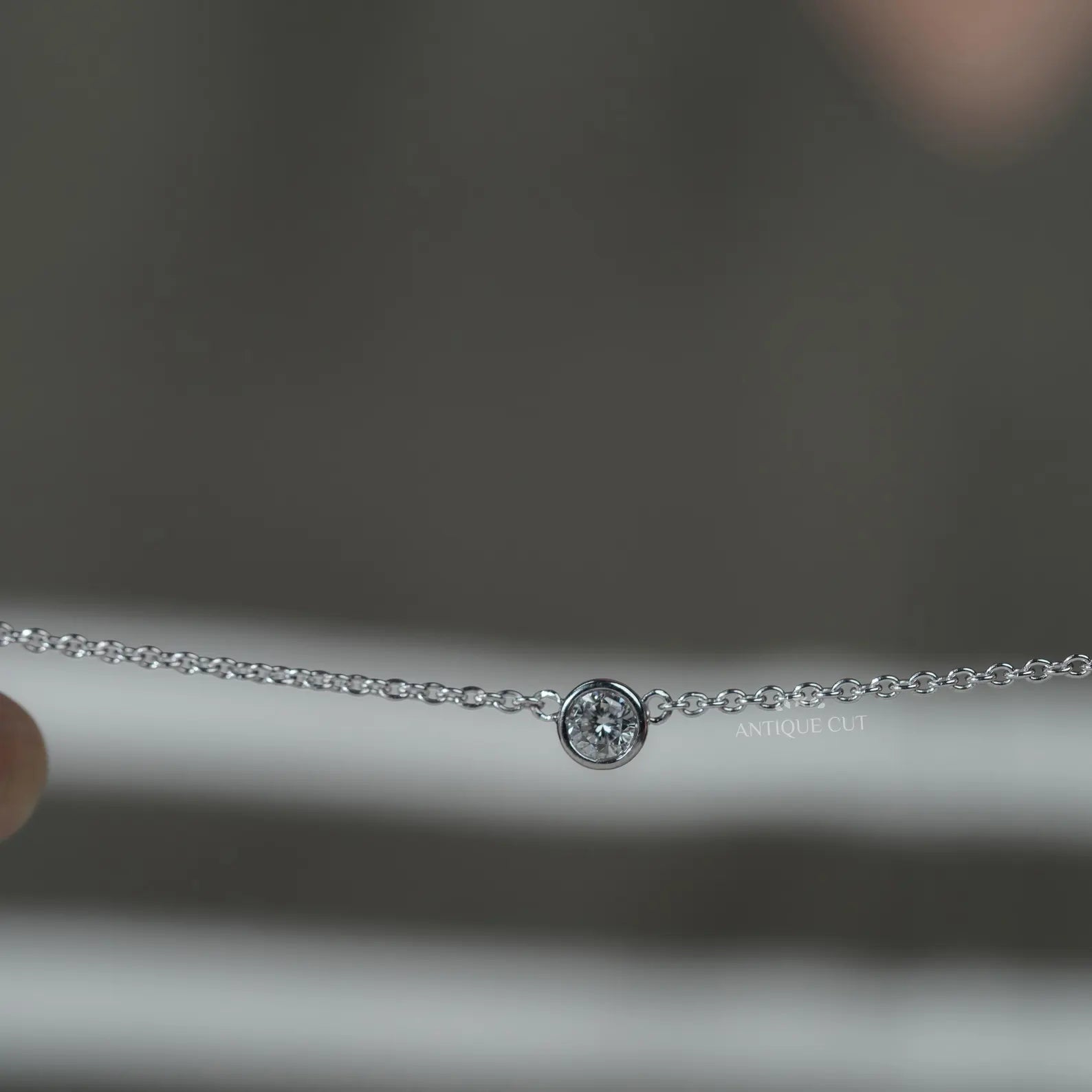 Silver necklace with small diamonds on a person wearing a green top
