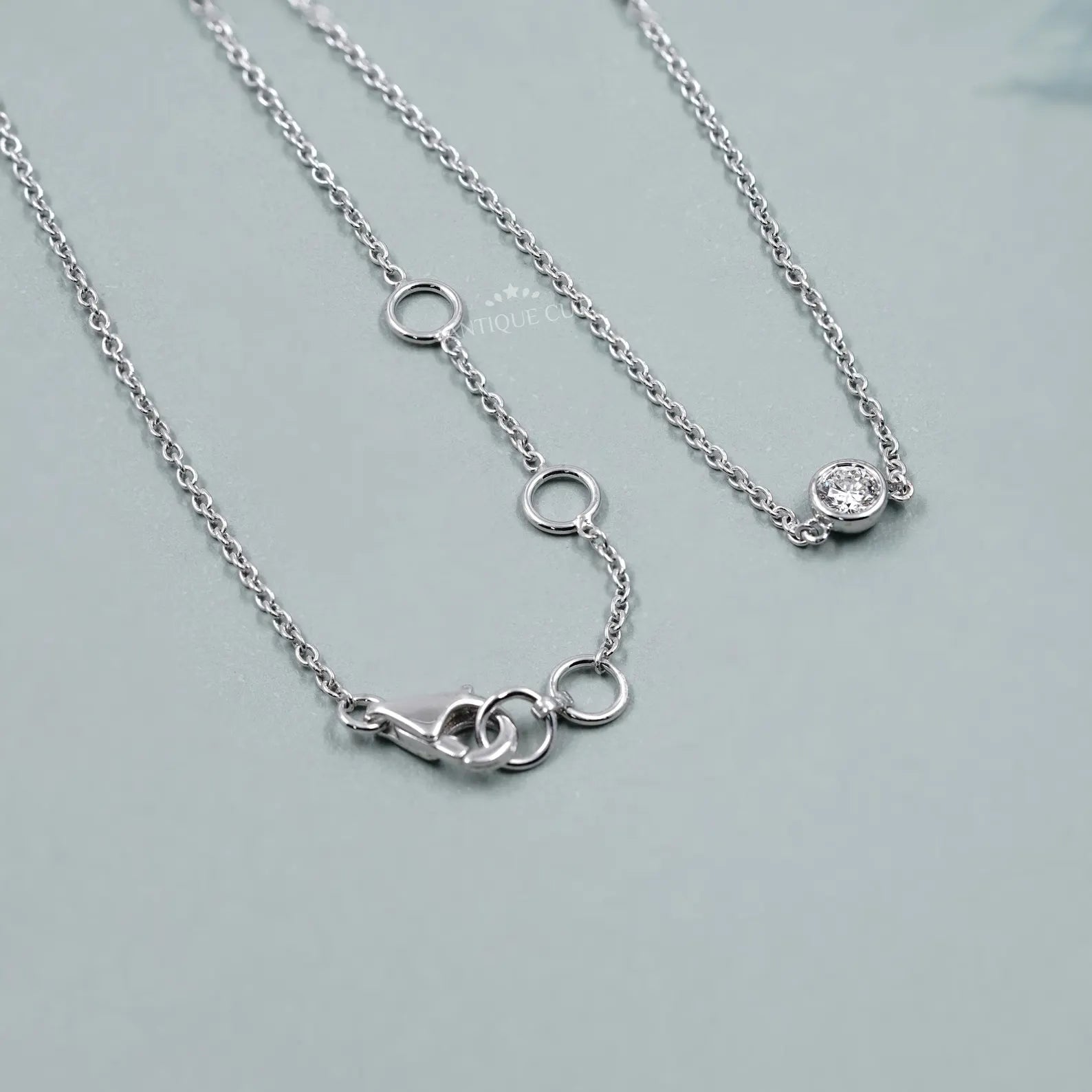 Silver necklace with small diamonds on a person wearing a green top