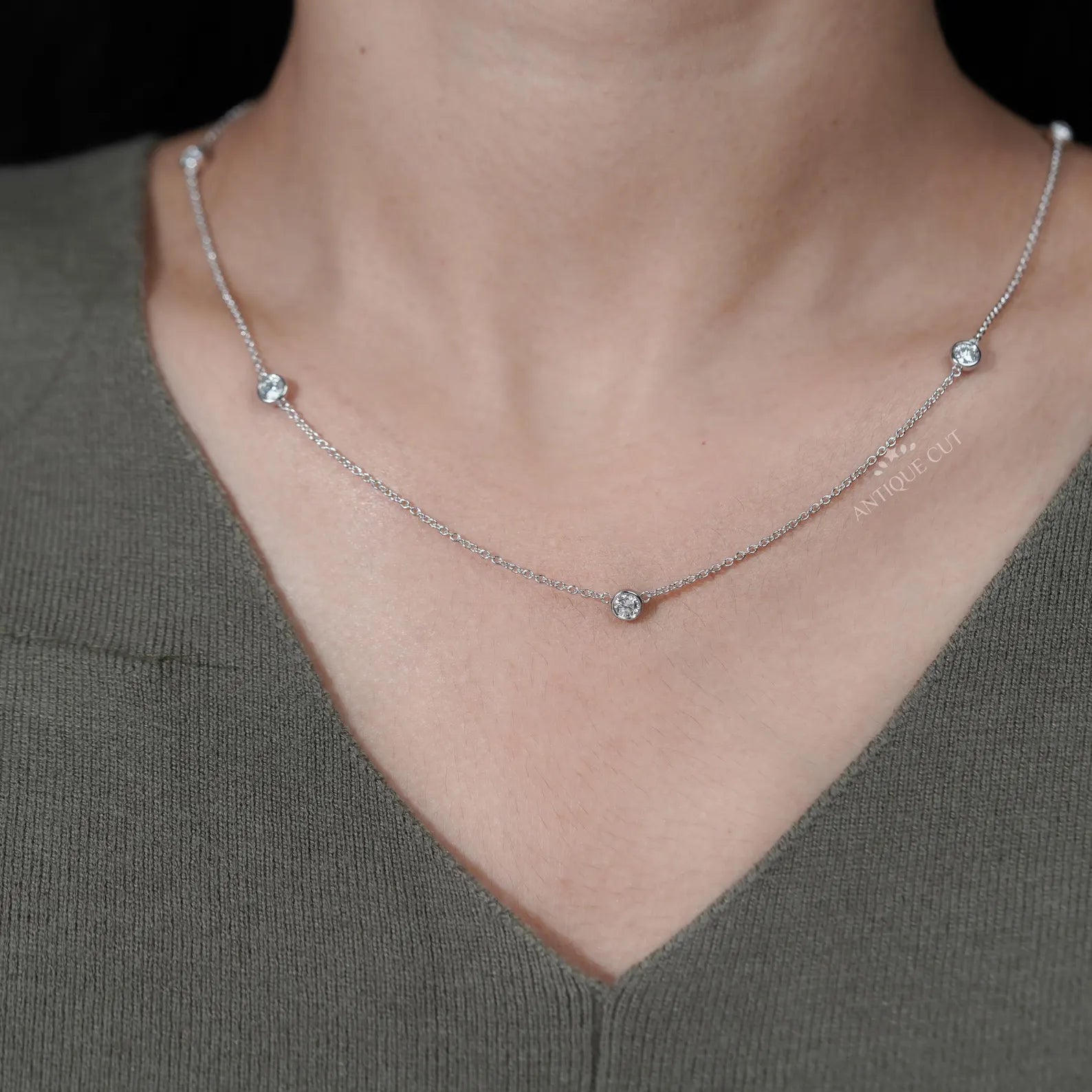 Silver necklace with small diamonds on a person wearing a green top