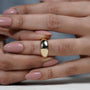 Close-up of a hand wearing a gold ring with a blurred background

