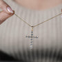 Gold cross necklace with diamonds on a person's neck

