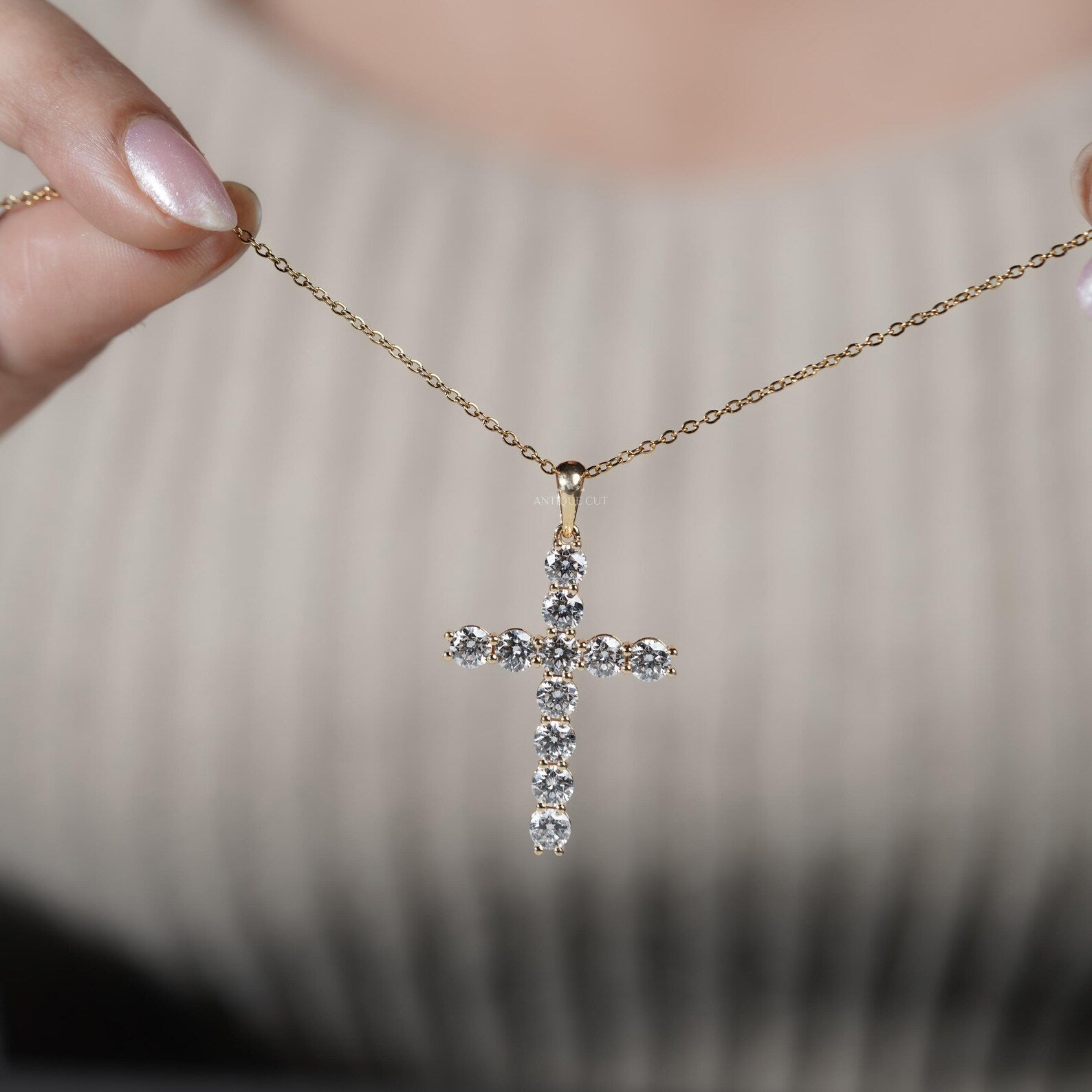Gold cross necklace with diamonds on a person's neck

