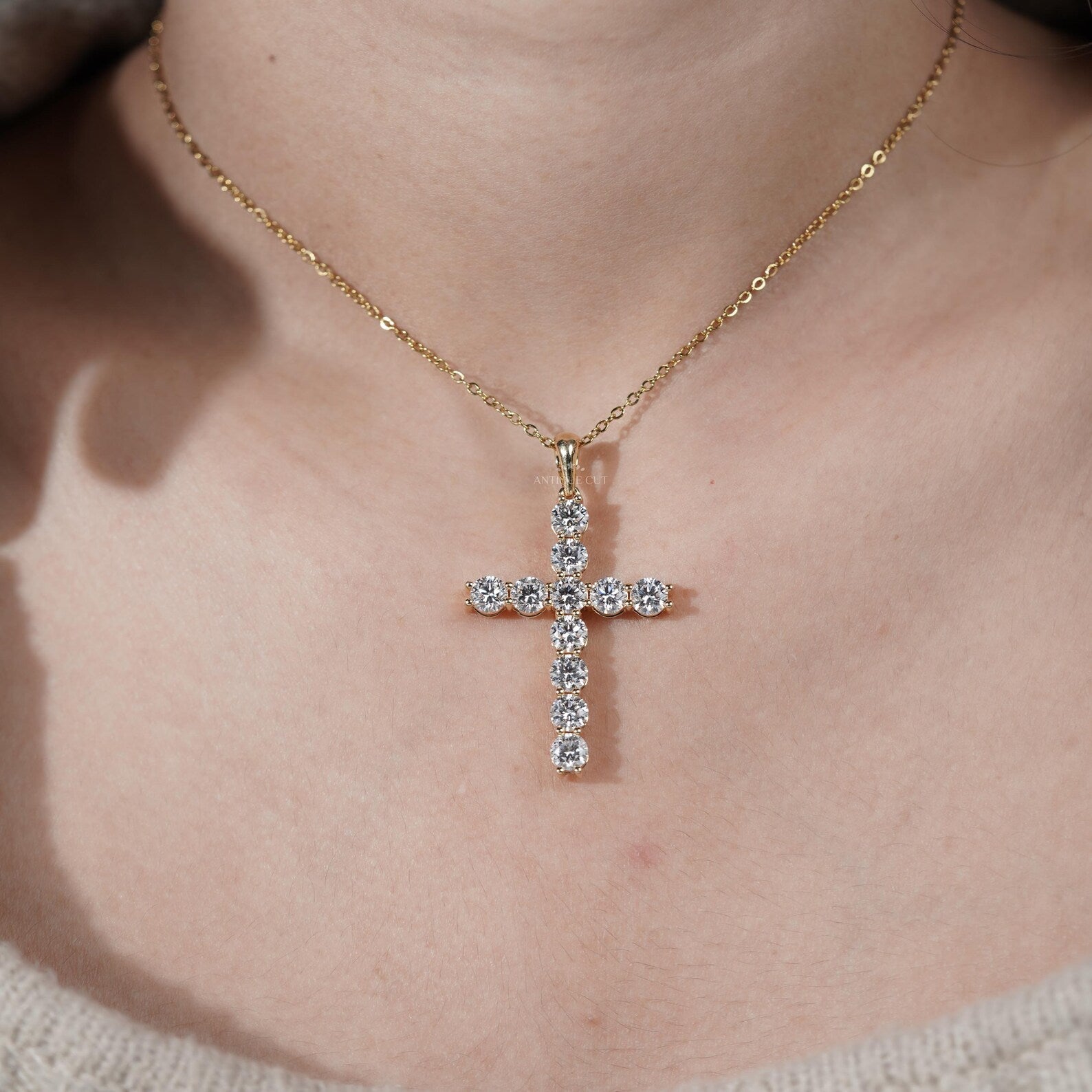 Gold cross necklace with diamonds on a person's neck

