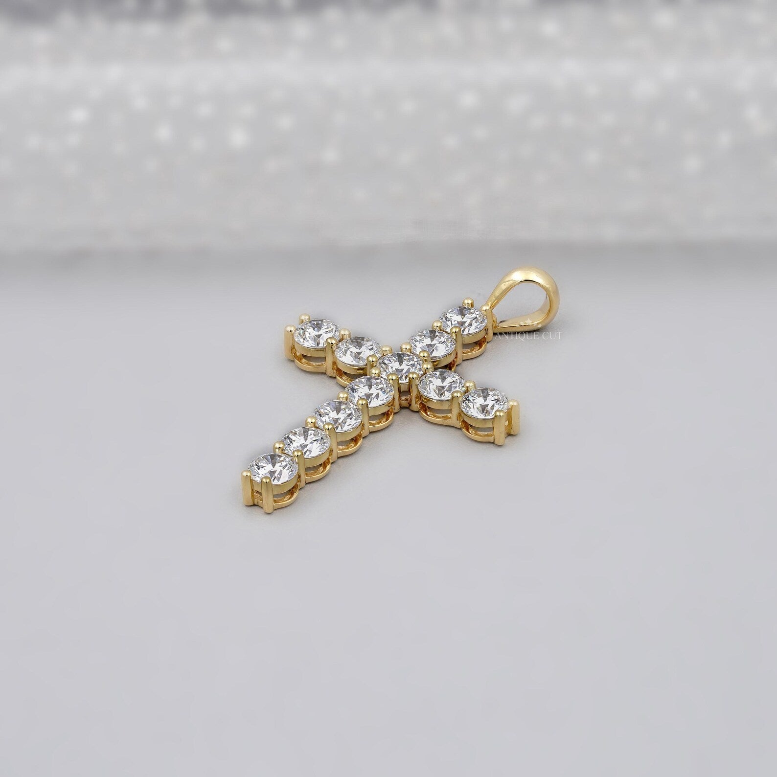 Gold cross necklace with clear stones on a gray background
