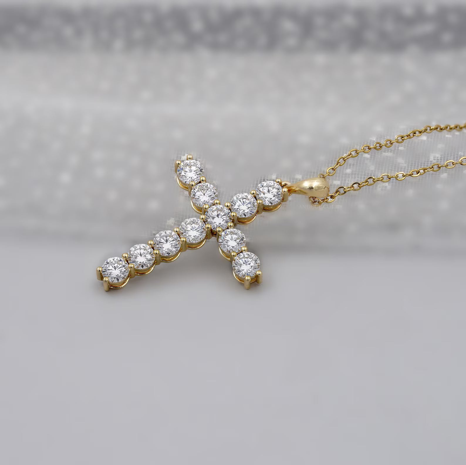 Gold cross necklace with clear stones on a gray background