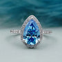 Teardrop shaped engagement ring with blue diamond halo