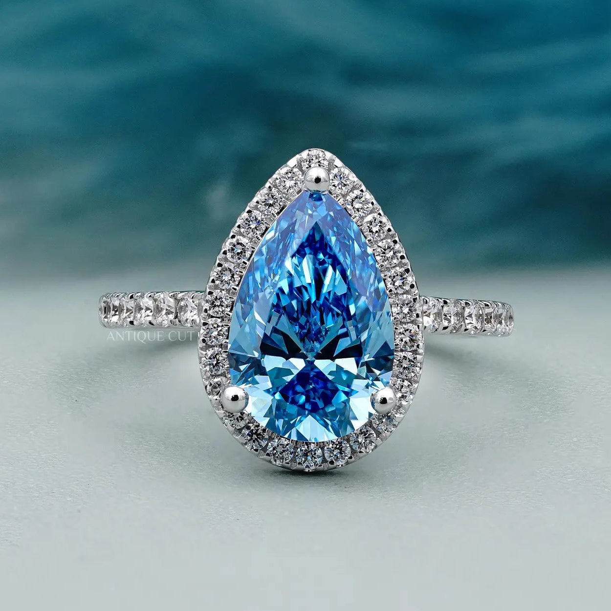 Teardrop shaped engagement ring with blue diamond halo