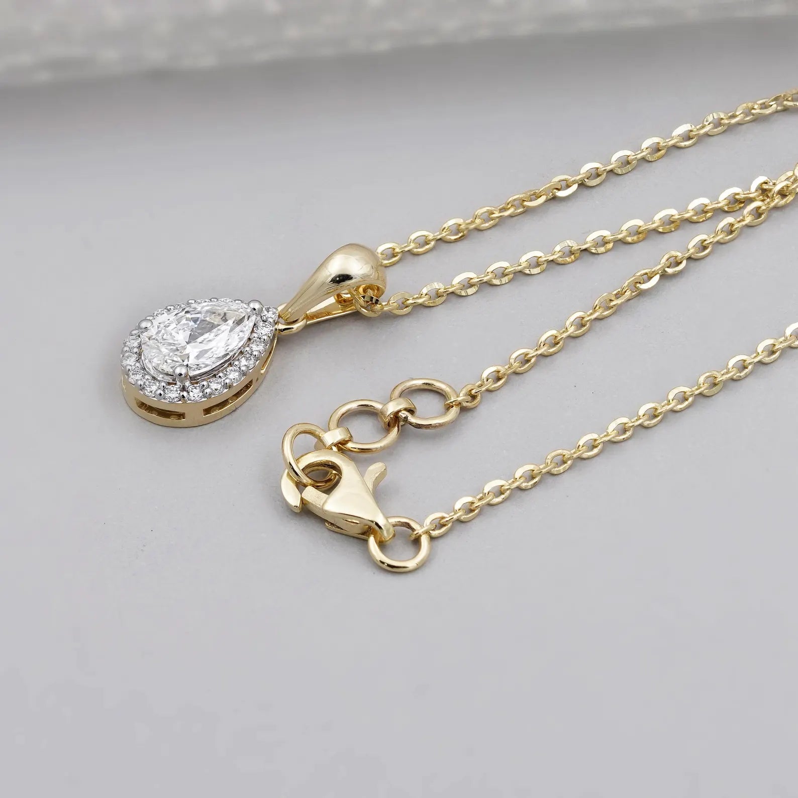 Pear cut halo diamond pendant with three prong setting