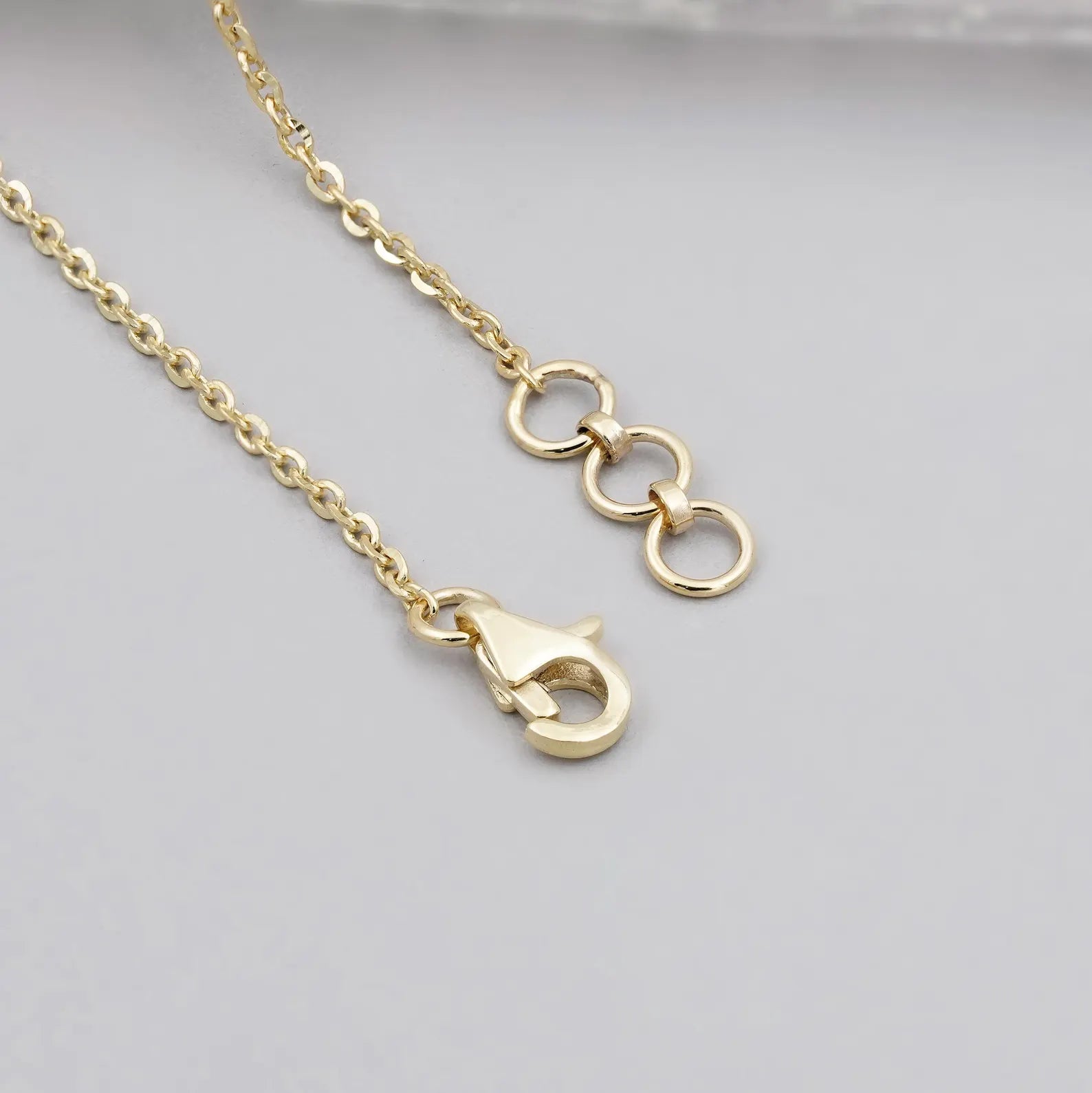 Detailed view of a polished yellow gold chain featuring a secure pendant bail and lobster clasp closure.