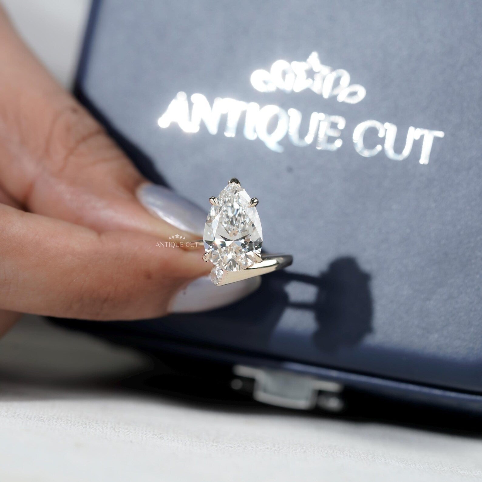 Pear shaped center diamond ring with side stones and V prong setting