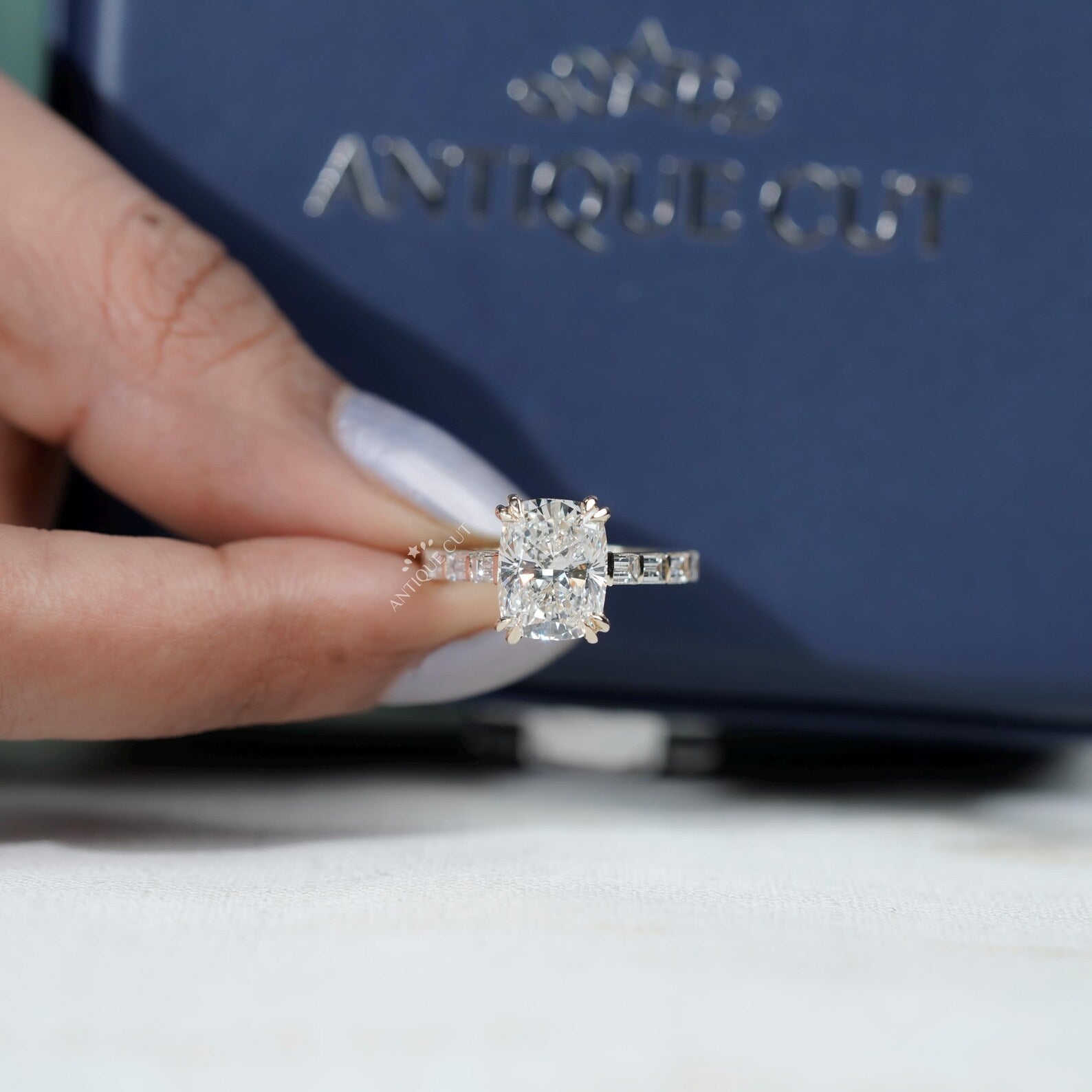 Cushion cut diamond ring with pavé band and double claw prongs in yellow gold