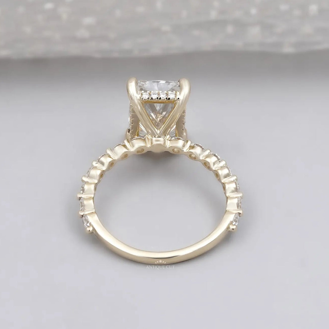 Radiant cut engagement ring in yellow gold with hidden halo and diamond pavé band