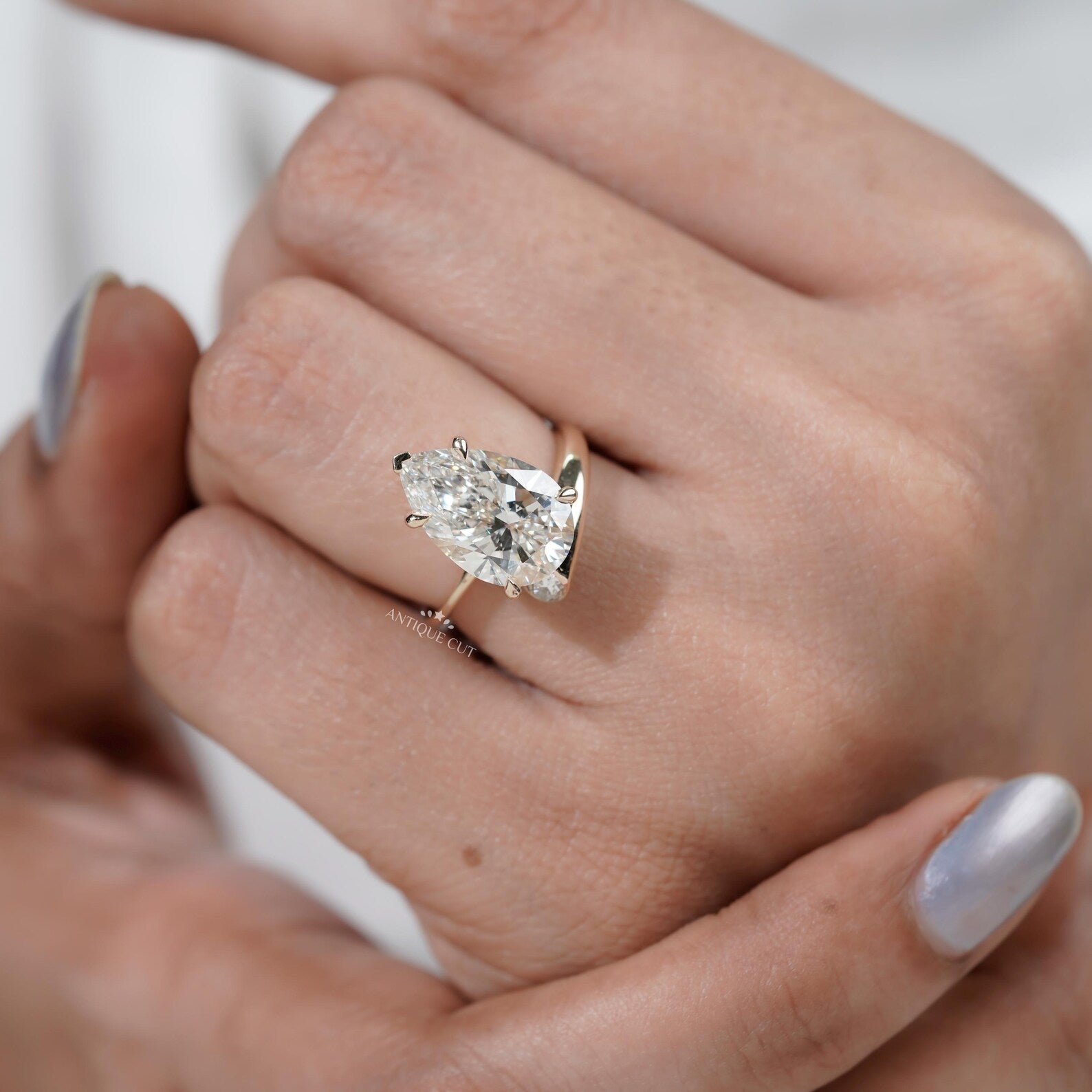 Yellow gold engagement ring with pear shaped center diamond and side stones