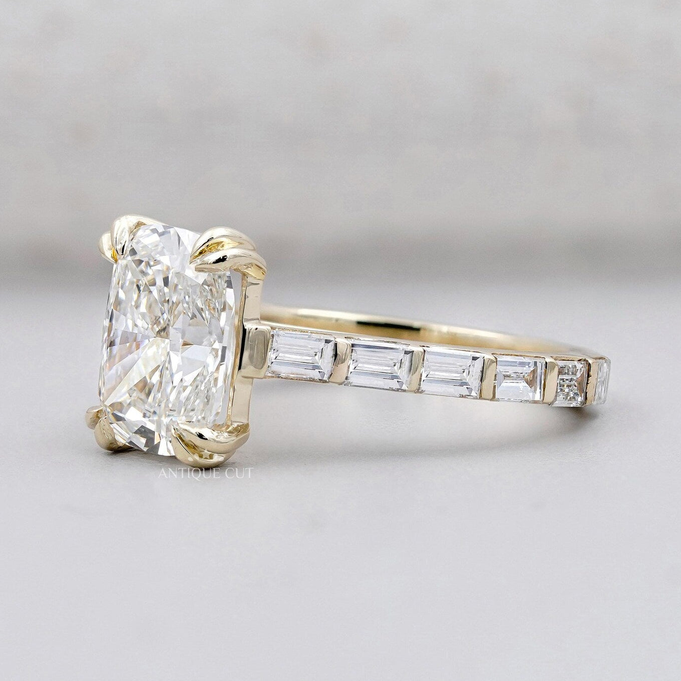 Yellow gold cushion cut engagement ring with double claw prongs and pavé diamonds