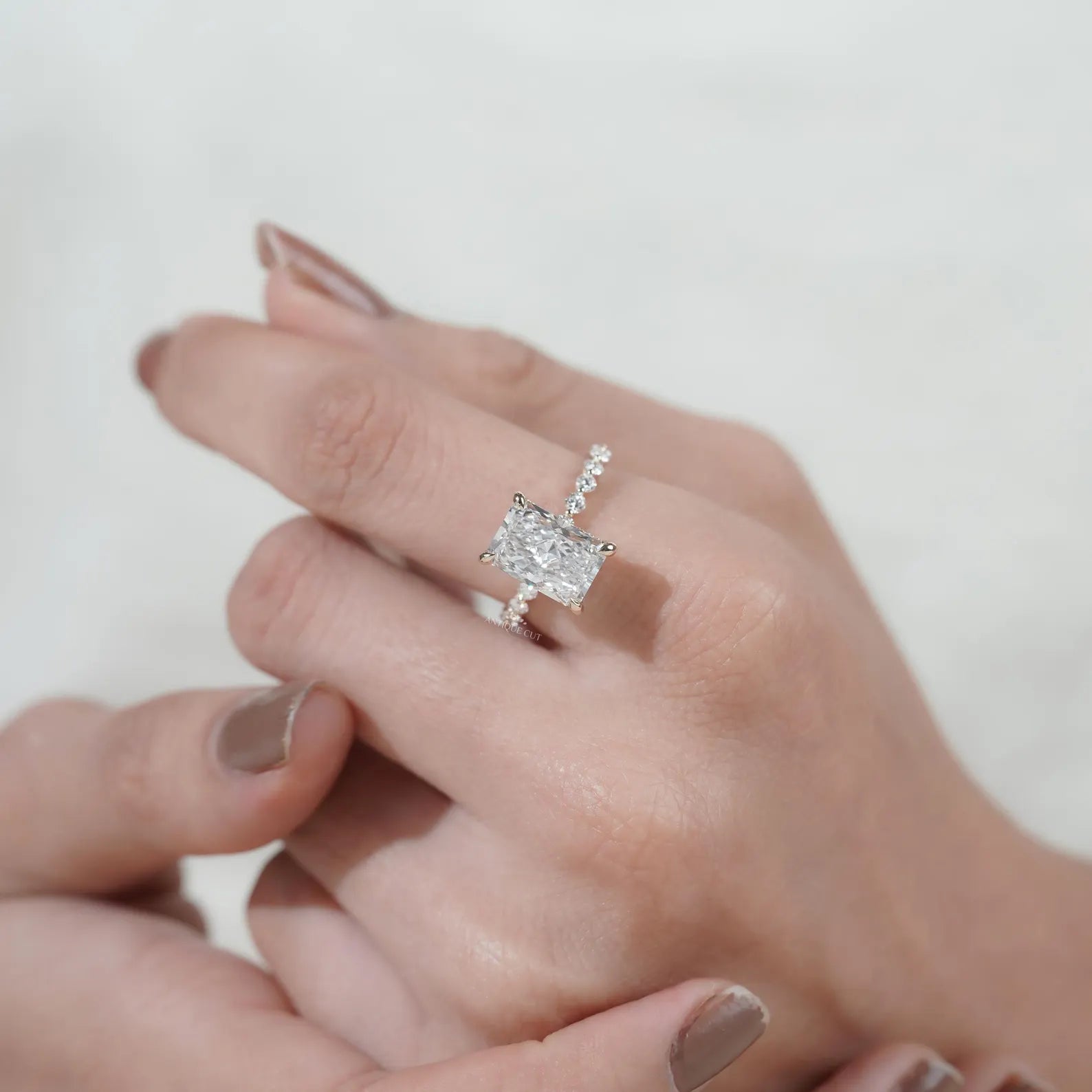 Radiant cut diamond ring with claw prong setting, pavé band, and yellow gold finish