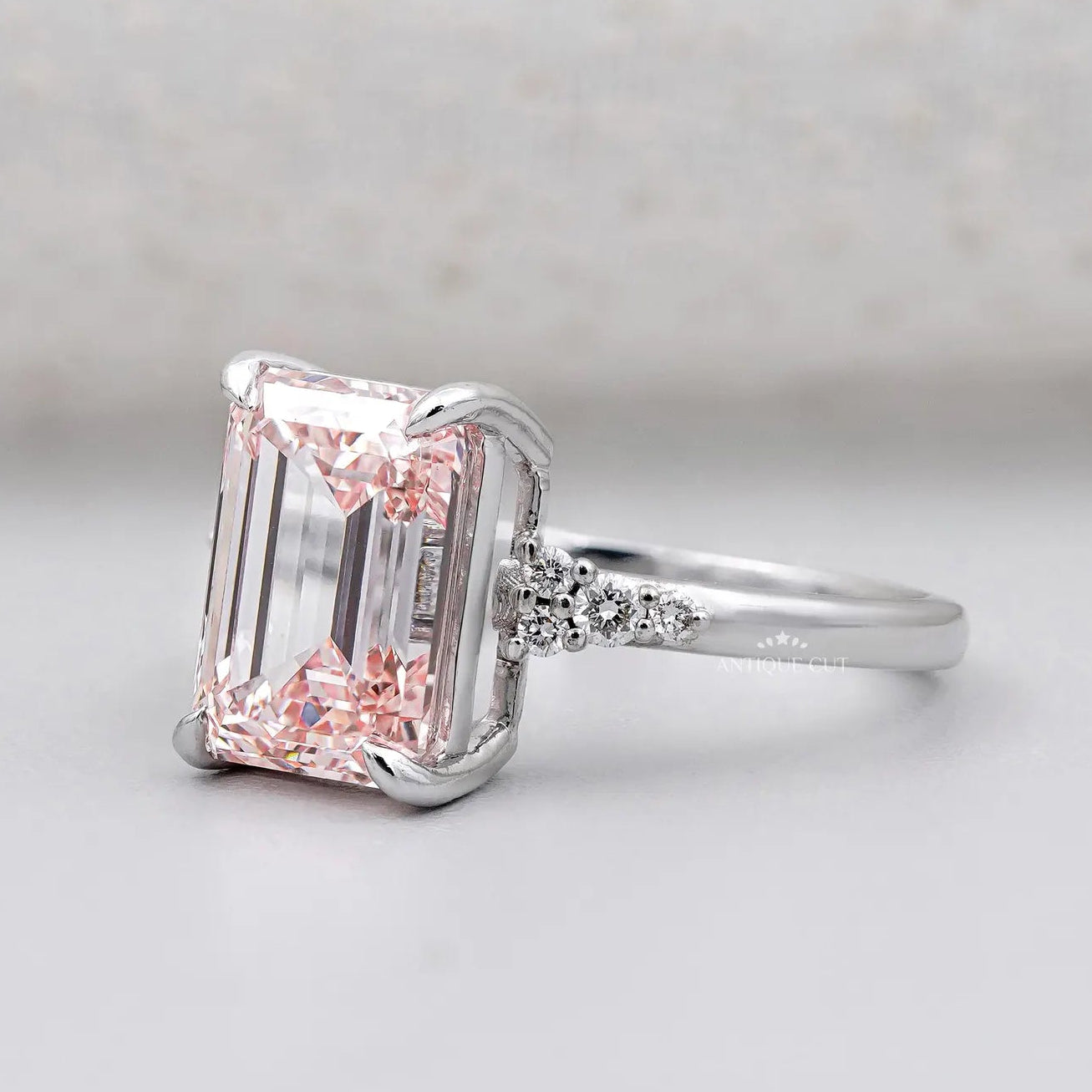 Emerald cut lab grown pink diamond ring with cluster side stones