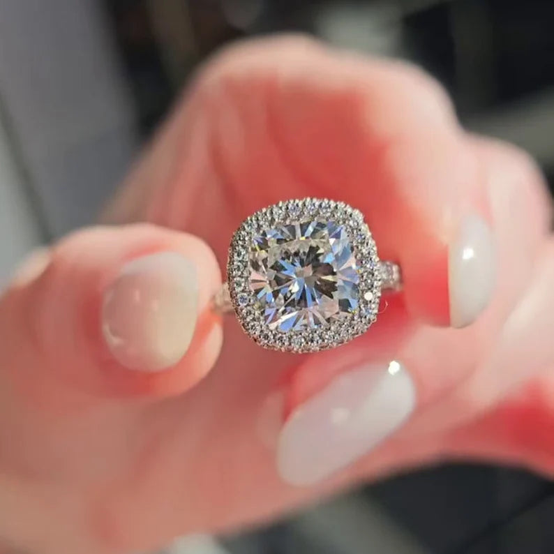 Cushion cut diamond engagement ring shown close up on hand