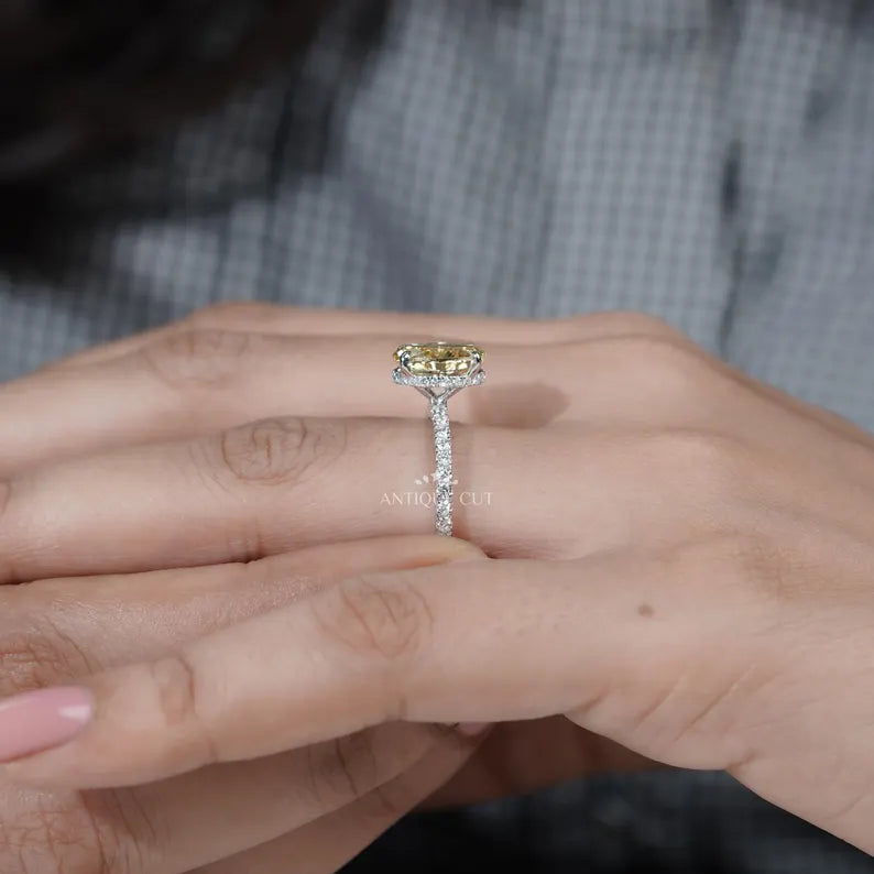 Close-up of a hand wearing a yellow diamond ring with a blurred background

