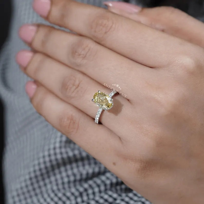 Close-up of a hand wearing a yellow diamond ring with a blurred background

