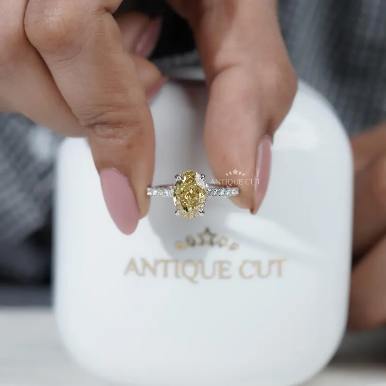 Gold ring with a yellow gemstone held by a hand, displayed in an 'AntiqueCut' box.

