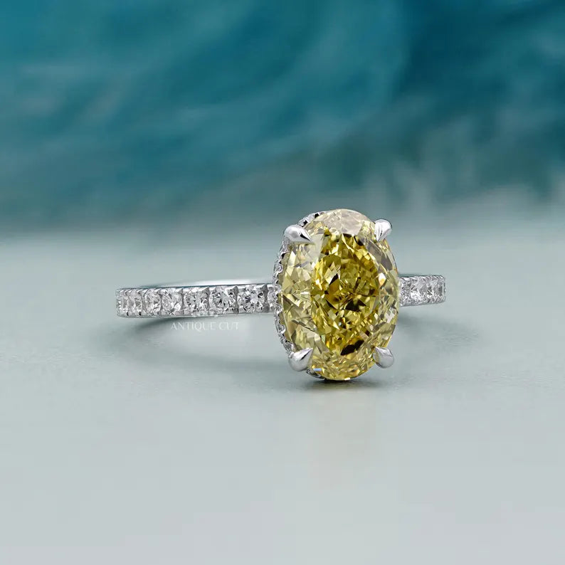 Ring with a yellow diamond and smaller diamonds on a light blue background